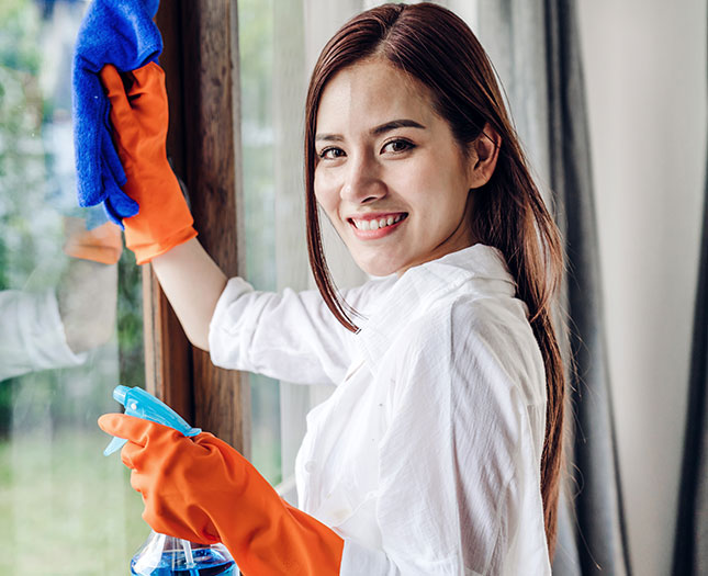 Kobieta z firmy sprzątające, myje okna podczas wykonywania usługi sprzątania apartamentów Wrocław